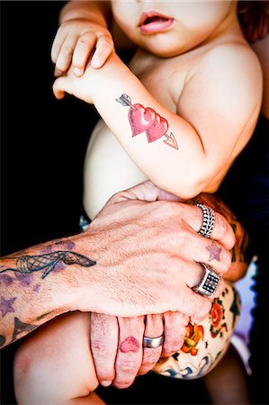 tattoed arms holding tattoed baby Stock Photo - Premium Royalty-Free, Code: 673-03405714