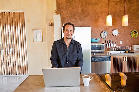 man working on laptop in kitchen Stock Photo - Premium Royalty-Free, Code: 673-03623279