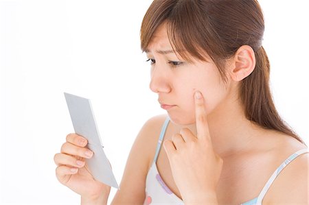 pimple - A young woman looking at pimple on her face Stock Photo - Premium Royalty-Free, Code: 685-02938539