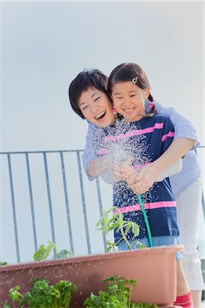 Mother and daughter watering plant on veranda Stock Photo - Premium Royalty-Free, Code: 685-03082734