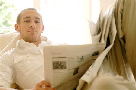 Young man reading newspaper on couch Stock Photo - Premium Royalty-Free, Code: 689-05610279