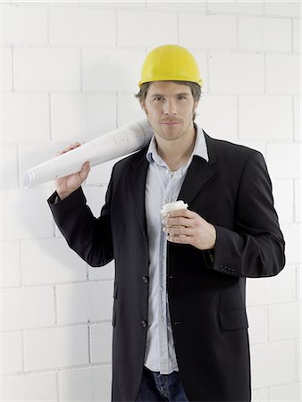 engineer helmet - Man wearing a helmet is holding a coffee cup and construction plan Stock Photo - Premium Royalty-Free, Code: 689-03130481