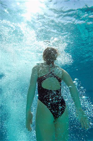 Woman coming up for air in pool, back view Stock Photo - Premium Royalty-Free, Code: 694-03319971