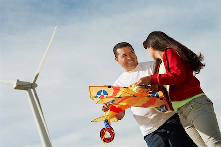 family smile kite - Girl (7-9) holding airplane kite with father at wind farm Foto de stock - Sin royalties Premium, Código: 694-03328176