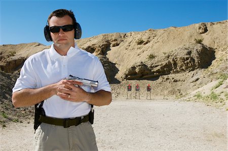 Man holding hand gun at firing range, portrait Stock Photo - Premium Royalty-Free, Code: 694-03328605