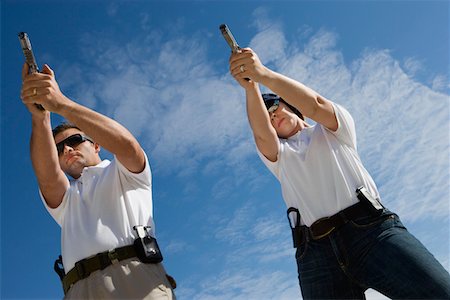Man and woman aiming hand guns at firing range, low angle view Stock Photo - Premium Royalty-Free, Code: 694-03328627