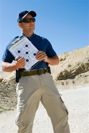 Instructor holding clipboard with target diagram at firing range Stock Photo - Premium Royalty-Free, Code: 694-03328643