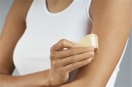Woman applying patch to arm, mid section Stock Photo - Premium Royalty-Free, Code: 694-03329017