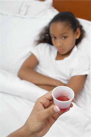 Hand holding medication for girl (7-9) lying in bed Stock Photo - Premium Royalty-Free, Code: 694-03329044