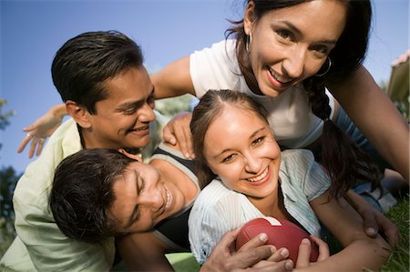 friends playing american football - Two young women and two young men playing football outdoors. Stock Photo - Premium Royalty-Free, Code: 694-03692290