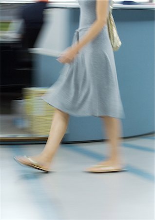 Woman in dress and flipflops walking, chest down, blurred motion Stock Photo - Premium Royalty-Free, Code: 695-05764155