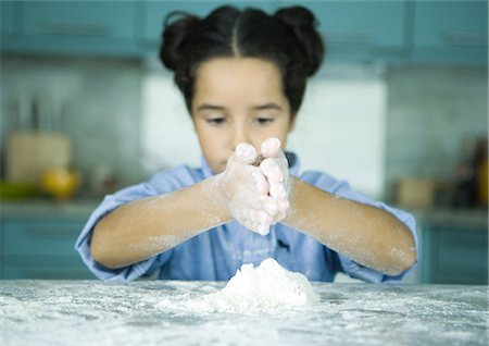 fun with flour - Girl standing at kitchen counter, holding hands over pile of flour Stock Photo - Premium Royalty-Free, Code: 695-05764219