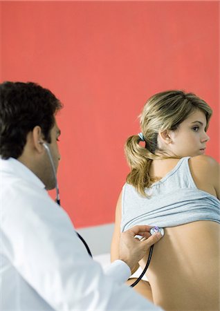 physician consulting backview - Doctor holding stethoscope against young woman's back Stock Photo - Premium Royalty-Free, Code: 695-05764383