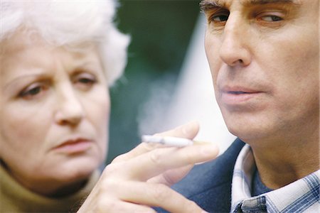 Senior man smoking, wife watching him Stock Photo - Premium Royalty-Free, Code: 695-05764706