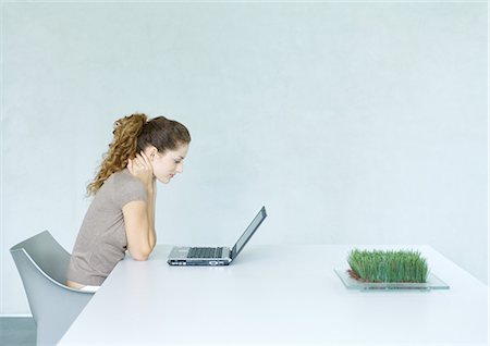 Woman using laptop, tray of wheatgrass on table Stock Photo - Premium Royalty-Free, Code: 695-05764824