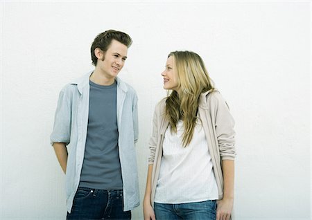 Young man and teenage girl standing side by side, smiling at each other Stock Photo - Premium Royalty-Free, Code: 695-05765119