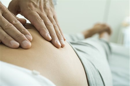 pregnant woman with doctor - Man's hands on pregnant woman's stomach Stock Photo - Premium Royalty-Free, Code: 695-05765466
