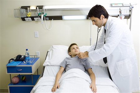 patient standing in hospital room - Enfant couché dans son lit d'hôpital, médecin debout de côté Photographie de stock - Premium Libres de Droits, Code: 695-05765963