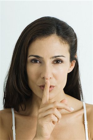 shhh - Woman holding finger over lips, looking at camera, portrait Stock Photo - Premium Royalty-Free, Code: 695-05766187