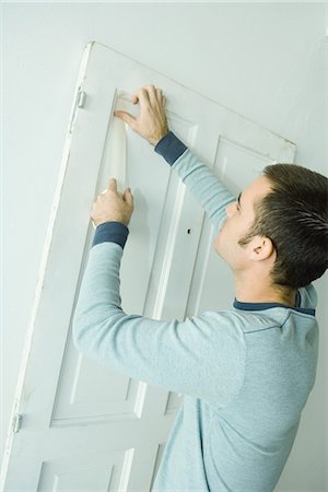 Man putting tape on door woodwork in preparation for painting Stock Photo - Premium Royalty-Free, Code: 695-05766291