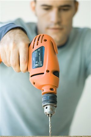 drilling (activity) - Man using drill, focus on drill in foreground Stock Photo - Premium Royalty-Free, Code: 695-05766302