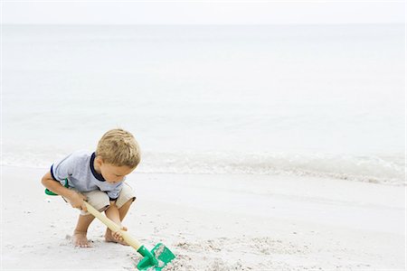 shovel (hand tool for digging) - Young boy crouching at the beach, digging in sand with shovel Stock Photo - Premium Royalty-Free, Code: 695-05767241