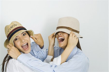 friends silly - Two young friends pulling hats over each other's faces and smiling, one looking at camera Stock Photo - Premium Royalty-Free, Code: 695-05767309