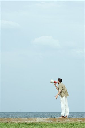 speaker (audio equipment) - Man standing by the sea, shouting into megaphone, side view Stock Photo - Premium Royalty-Free, Code: 695-05767583