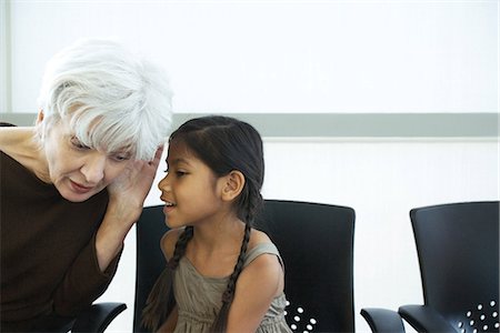 pictures of a little girl whispering - Little girl whispering in grandmother's ear, both looking away Stock Photo - Premium Royalty-Free, Code: 695-05767598