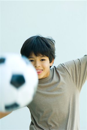 Little boy playing with soccer ball, arms out, smiling at camera Stock Photo - Premium Royalty-Free, Code: 695-05767825