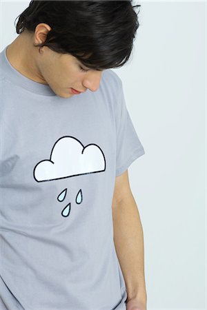 rainy day sad - Young man wearing tee-shirt printed with cloud and raindrops, head down Stock Photo - Premium Royalty-Free, Code: 695-05767883