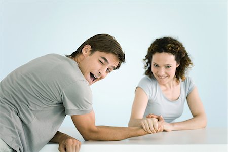 Couple arm wrestling, both looking at camera, man winking as he lets woman win Stock Photo - Premium Royalty-Free, Code: 695-05767891