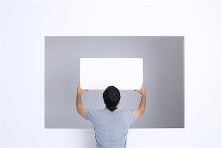 Man holding up blank sign, rear view Stock Photo - Premium Royalty-Free, Code: 695-05767932