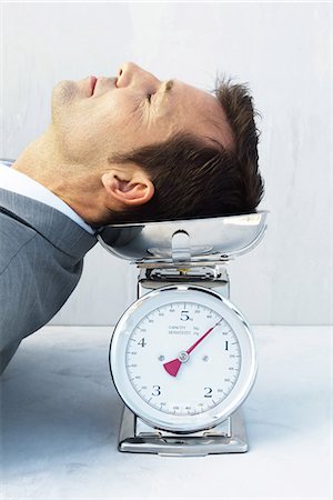 Man resting head on scale, eyes closed Stock Photo - Premium Royalty-Free, Code: 695-05768157