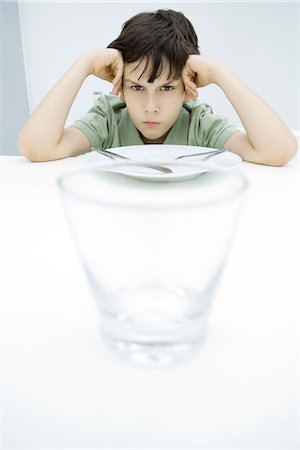 simsearch:695-03380694,k - Boy sulking at kitchen table, leaning on elbows, empty glass in foreground Stock Photo - Premium Royalty-Free, Code: 695-05768258