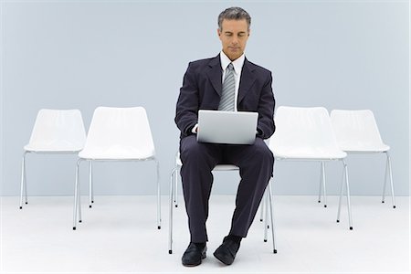 Business man sitting alone in room using laptop computer Stock Photo - Premium Royalty-Free, Code: 695-05768509