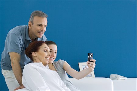 Family leaning together for photograph, daughter hold out cell phone Stock Photo - Premium Royalty-Free, Code: 695-05768613