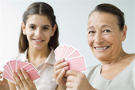 Grandmother and granddaughter playing cards, smiling at camera Stock Photo - Premium Royalty-Free, Code: 695-05768694