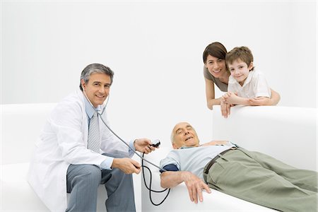 simsearch:700-02121243,k - Doctor measuring elderly man's blood pressure, family leaning on couch, all smiling at camera Stock Photo - Premium Royalty-Free, Code: 695-05768769
