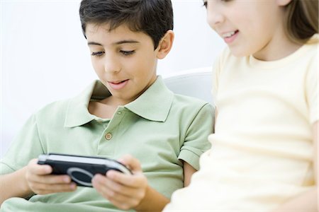 simsearch:632-03424261,k - Brother and sister sitting together, boy playing handheld video game Stock Photo - Premium Royalty-Free, Code: 695-05768894