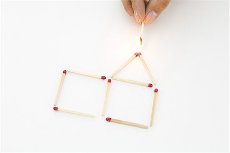 studio creative group - Hand holding lit match to house made of matches Stock Photo - Premium Royalty-Free, Code: 695-05768945