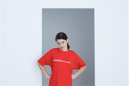 Preteen girl wearing tee-shirt printed with e-mail address, hands on hips, looking at camera Stock Photo - Premium Royalty-Free, Code: 695-05768992