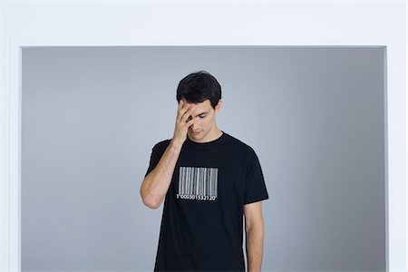 Man wearing tee-shirt printed with bar code, covering face with hand Stock Photo - Premium Royalty-Free, Code: 695-05769011