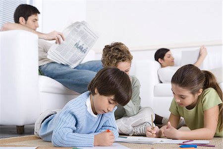 simsearch:695-03378605,k - Children coloring on the floor in living room, parents reading in background Stock Photo - Premium Royalty-Free, Code: 695-05769092