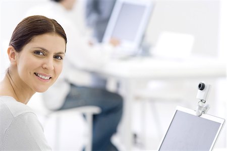 Woman in office, smiling over shoulder at camera Stock Photo - Premium Royalty-Free, Code: 695-05769146