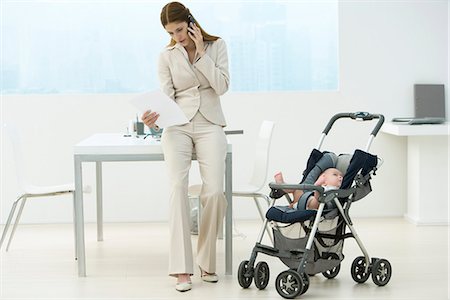 Professional woman in office with baby in stroller, talking on cell phone Stock Photo - Premium Royalty-Free, Code: 695-05769235