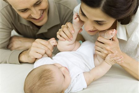 Parents smiling down at baby, mother holding baby's feet, cropped view Stock Photo - Premium Royalty-Free, Code: 695-05769254