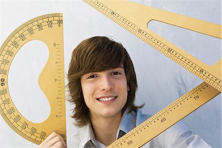 Young man holding various measuring instruments, smiling at camera Stock Photo - Premium Royalty-Free, Code: 695-05769283