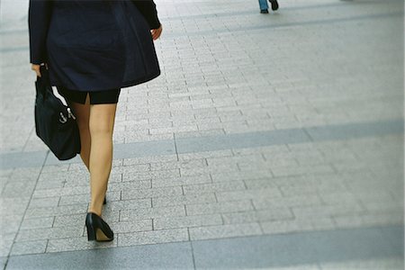 Businesswoman walking on sidewalk, rear view, cropped Stock Photo - Premium Royalty-Free, Code: 695-05769545