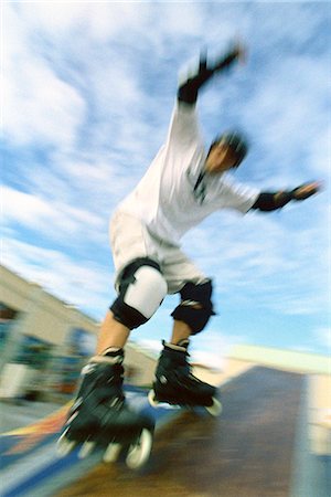 Inline skater with arms raised sliding on ramp at skatepark Stock Photo - Premium Royalty-Free, Code: 695-05769848